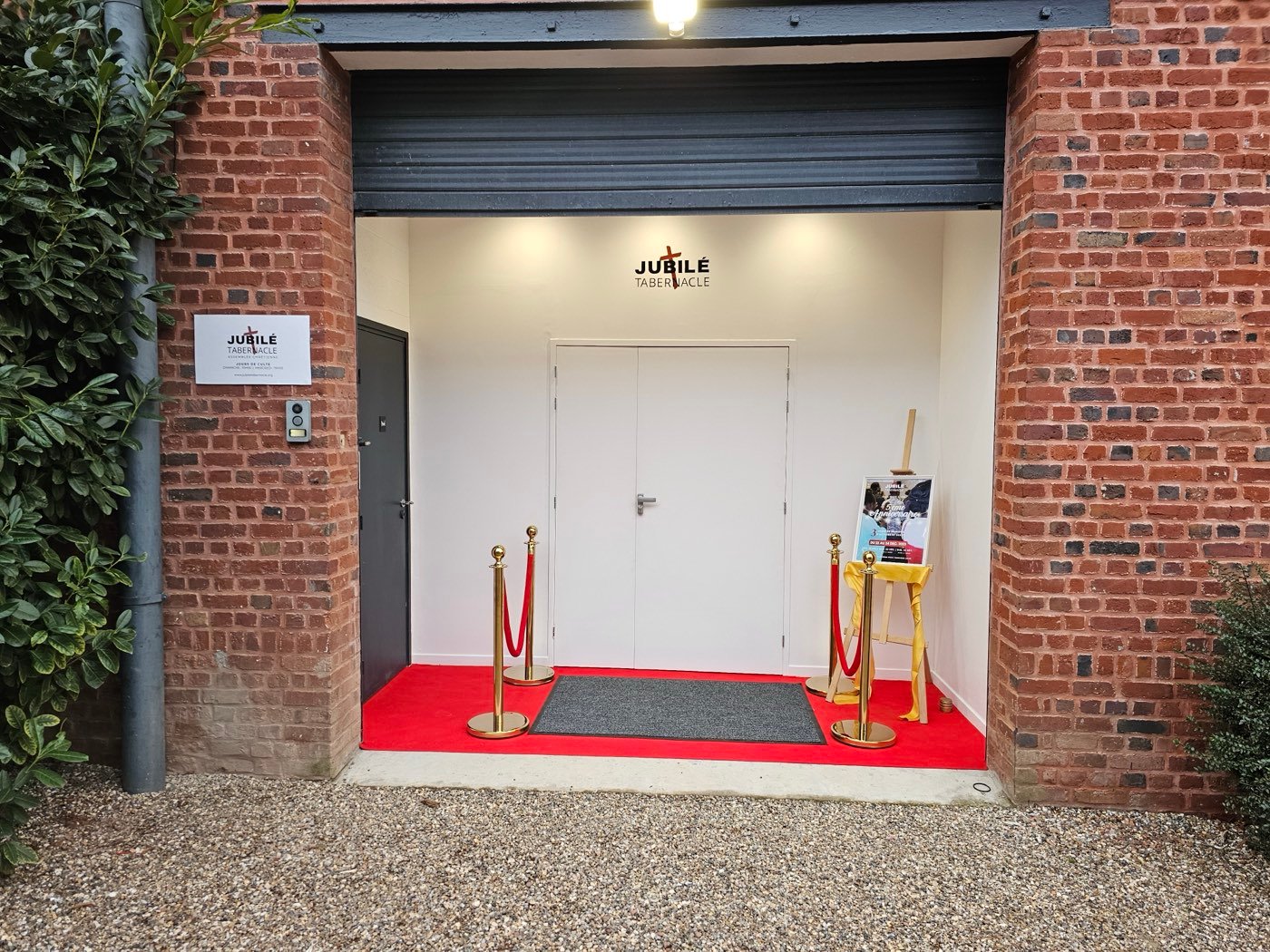 L'entrée de Jubilé Tabernacle : un porche en briques rouges avec l'enseigne et un tapis rouge
